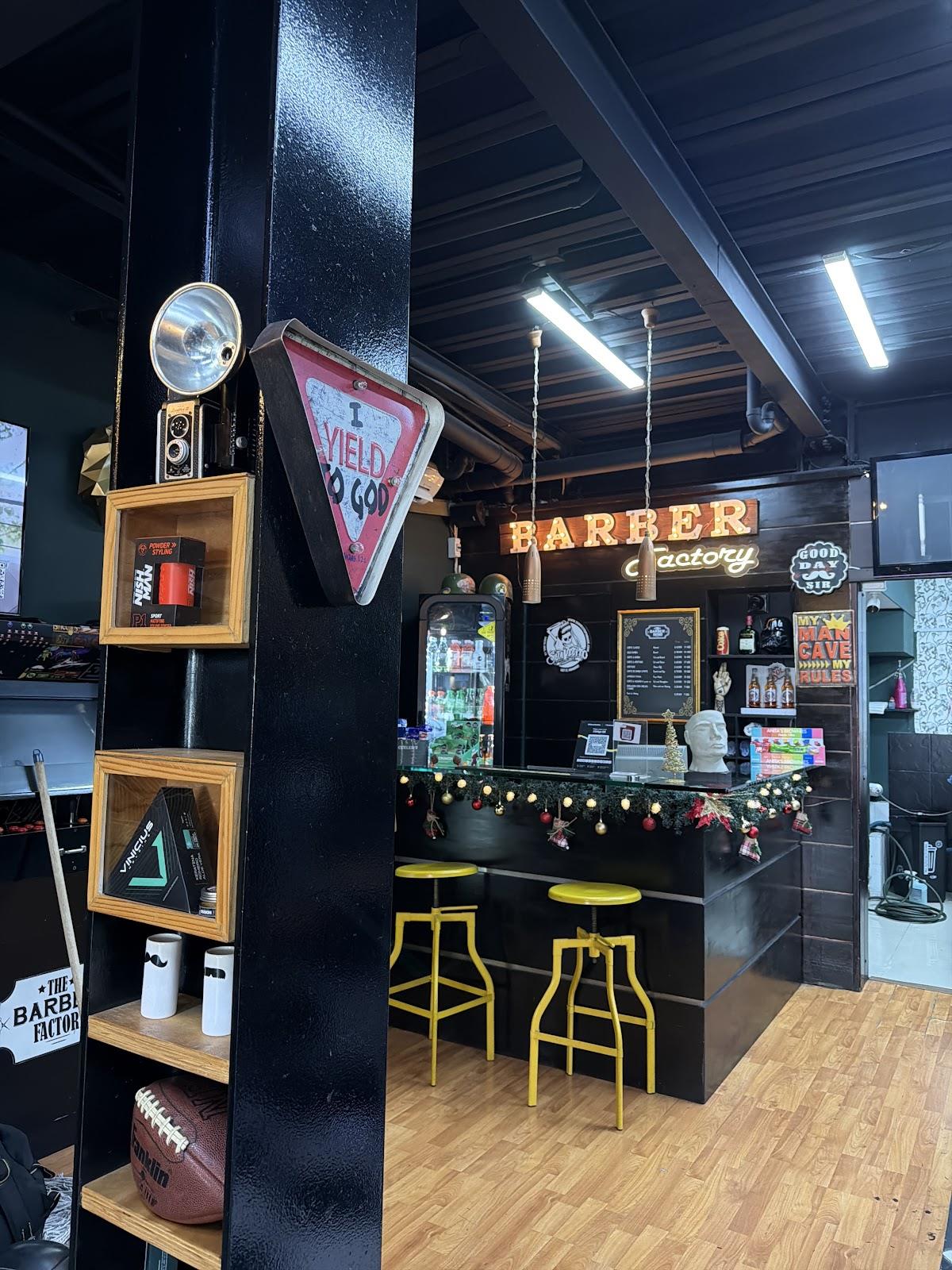 Interior de The Barber Factory: vigas negras, letras de bombillos BARBER y banquetas amarillas